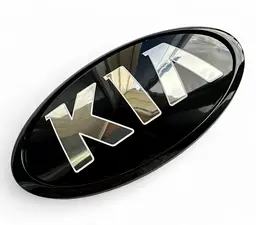 Емблема Kia СТАРОГО ТИПУ Чорна (старий шрифт) 130x65 мм (обід чорний) Пластик (на скотчі + 3 ніжки) (Завод)