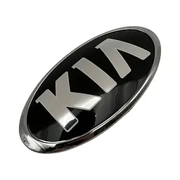 Емблема Kia СТАРОГО ТИПУ Чорна (старий шрифт) 114x57 мм (хромований обідок) Пластикова (на скотчі + 2 затискні ніжки) (Заводська)
