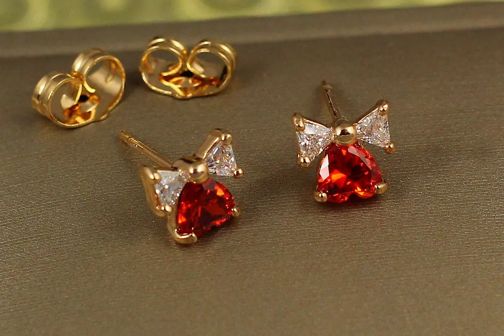 Сережки гвоздики Xuping Jewelry серце з бантиком із червоним каменем 7 мм золотисті